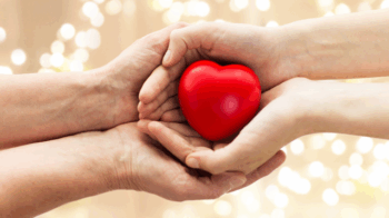 Two hands holding a red heart object.